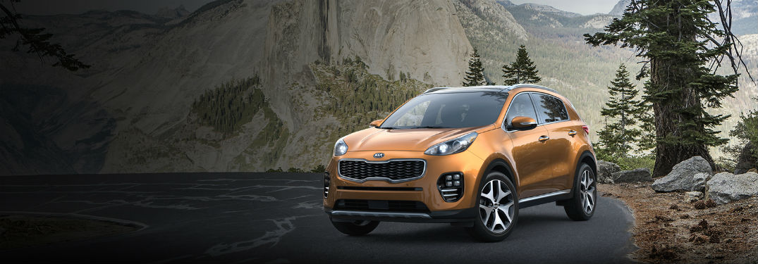 2018 Kia Sportage exterior front fascia and drivers side on a road with tree next to it