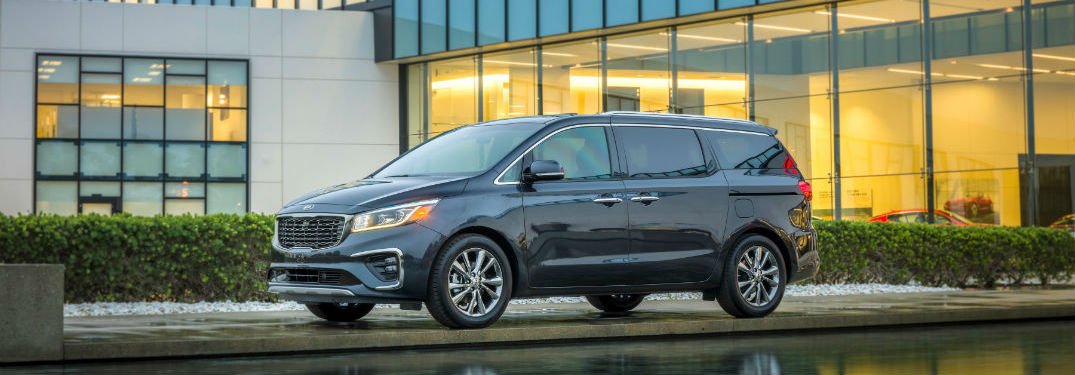 2019 Kia Sedona exterior front fascia and drivers side parked in front of glass window building