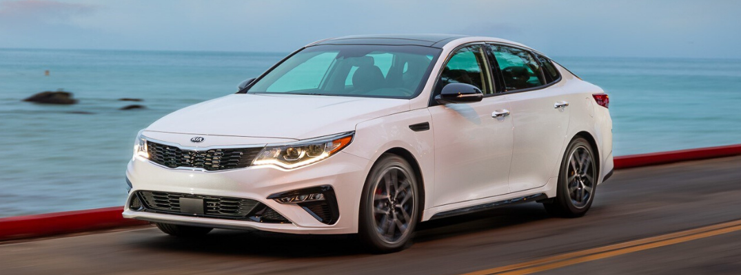 Front view of white 2020 Kia Optima on a road by the sea