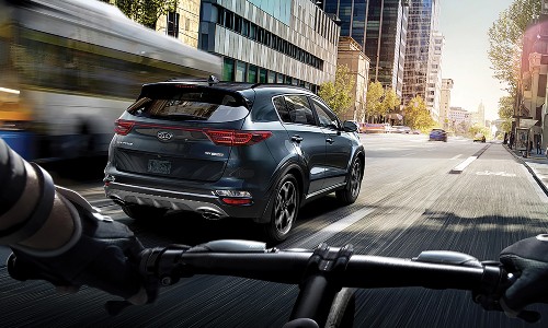 2020 Kia Sportage driving through city seen by bike cyclist