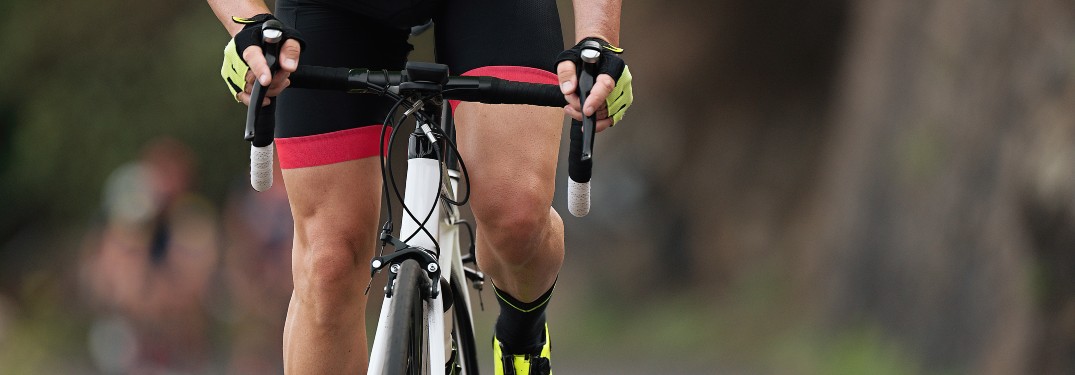 person on bicycle close up on knees and handlebars