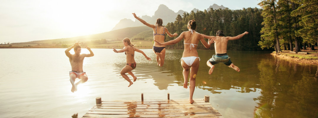 Young adults jumping into a lake during the summer