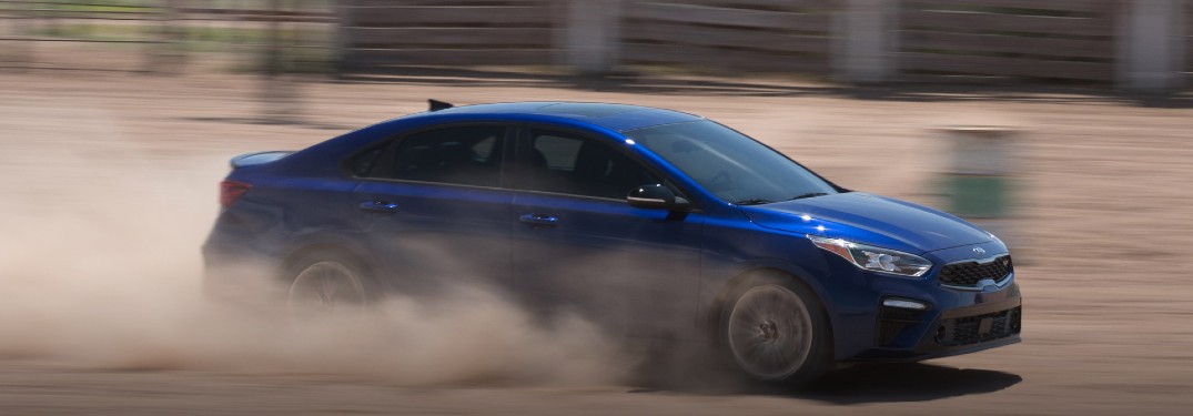 2021 Kia Forte blue exterior passenger side driving in sand