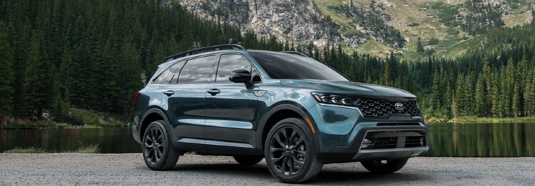 2021 Kia Sorento aqua exterior front fascia passenger side parked on shore of lake in forest with mountains