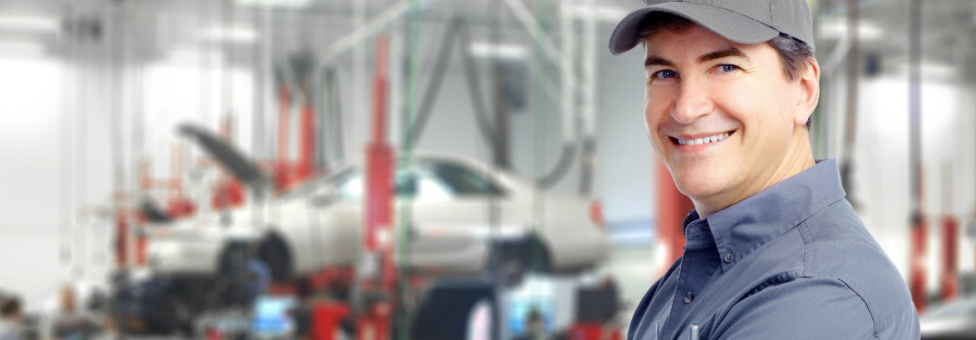Auto technician smiling in front of body shop