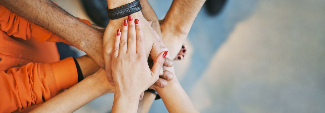 A group of hands stacked on top of each other for a cheer in a blog post about community involvement