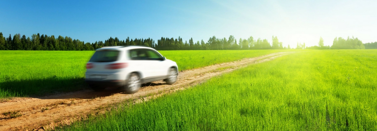 A car driving down a road in a field featured in a blog post about driving tips