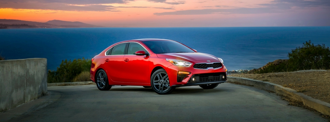 2019 Kia Forte Front View of Red Exterior with Sunset and Ocean Backdrop