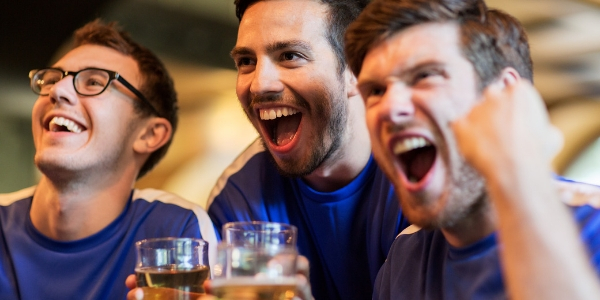Three guys cheering while holding beers