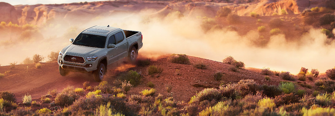 2018 Toyota Tacoma in gray driving on a dirt road in the desert