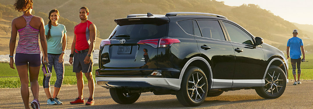 2018 Toyota RAV4 parked on a trail and surrounded by friends wearing workout clothes