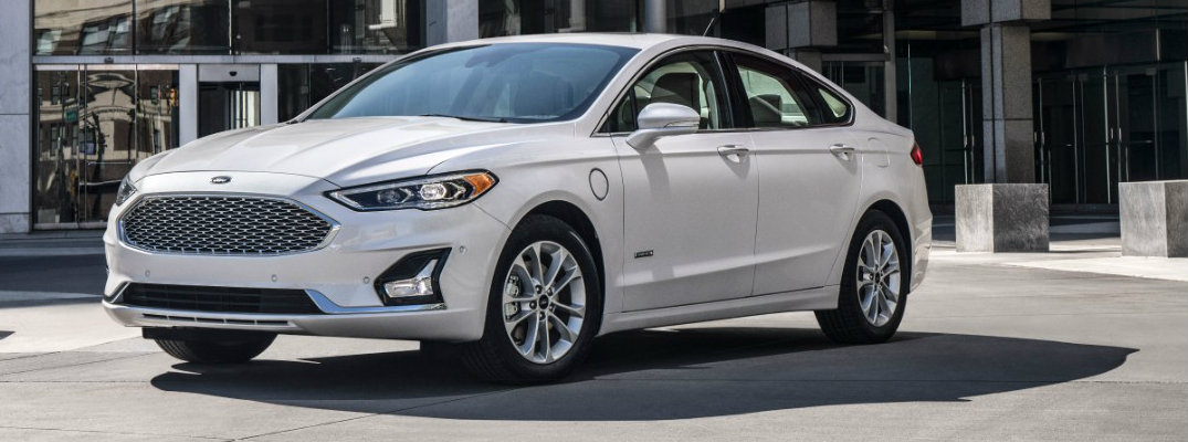 Profile view of white 2019 Ford Fusion Hybrid parked in front of building in daytime