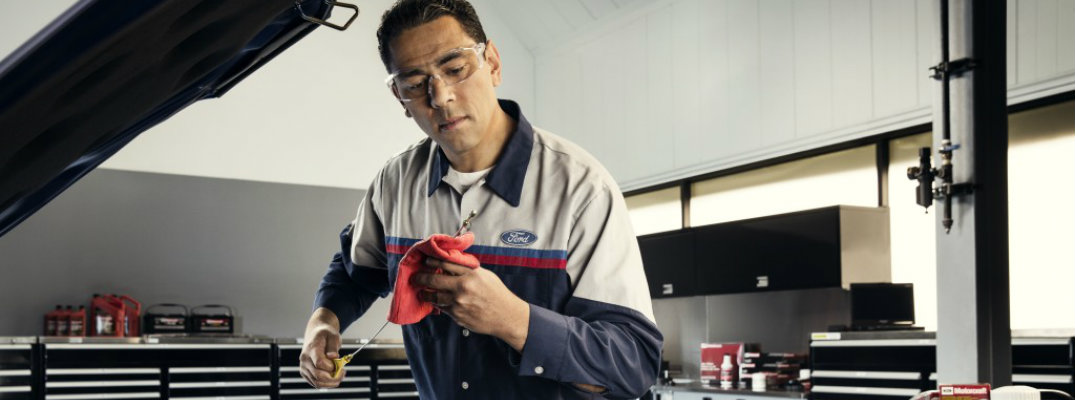 Ford mechanic checking dipstick in automotive service bay