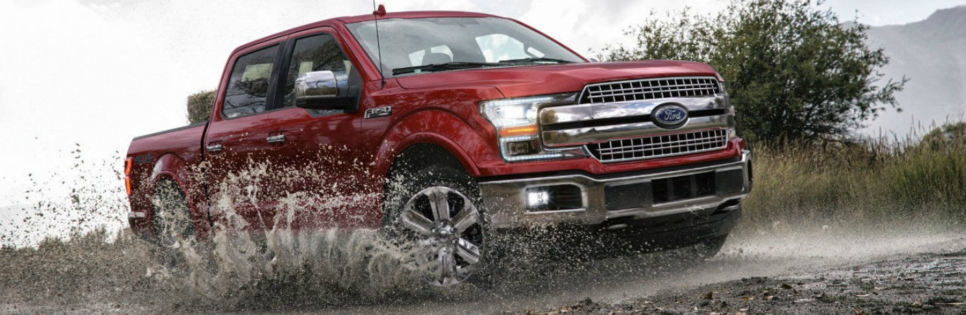 Red 2018 Ford F-150 driving through mud
