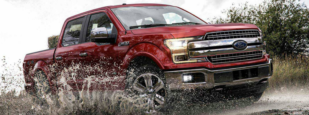 Red 2018 Ford F-150 driving through mud