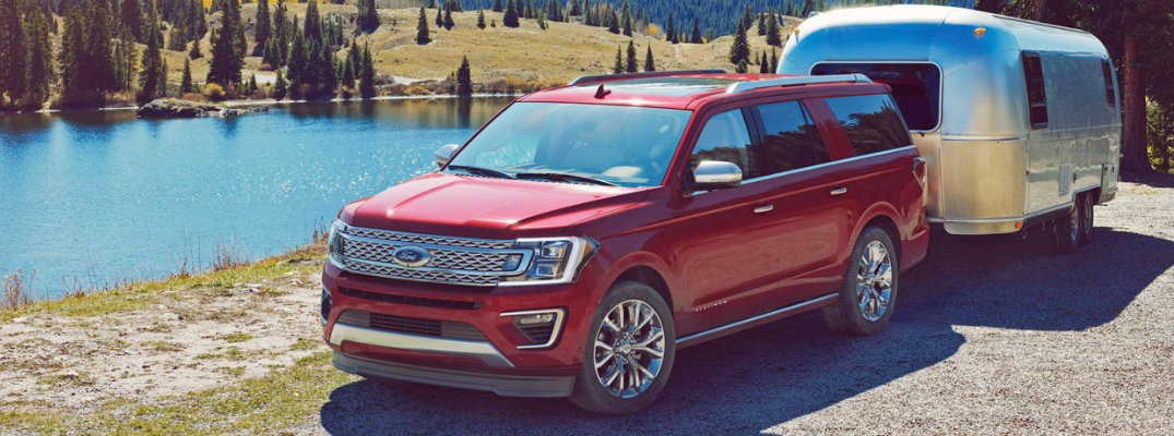 Red Ford Expedition parked next to wooded waterfront