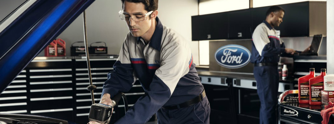 Two Ford mechanics in service bay working on vehicle