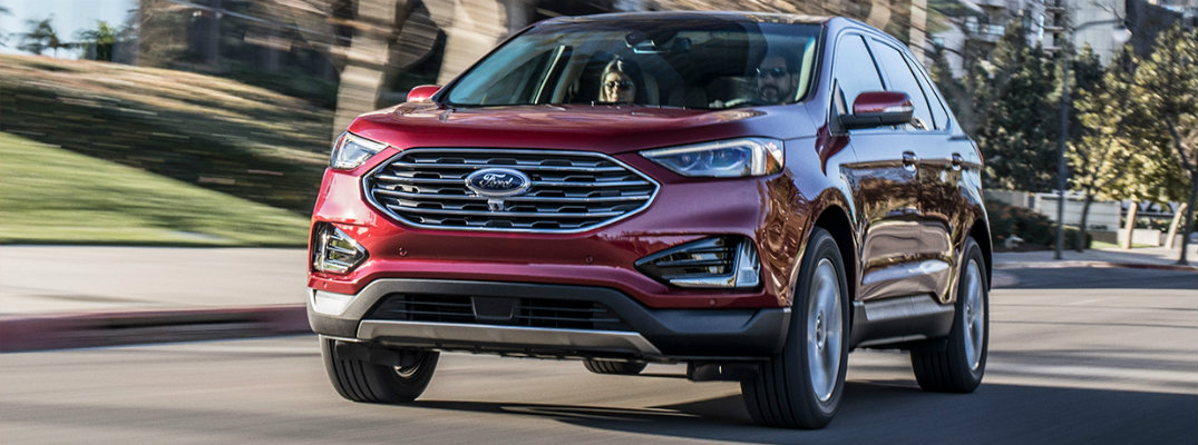 Red 2019 Ford Edge driving on busy city street
