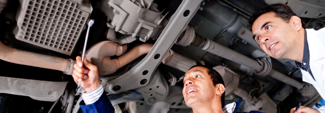 Mechanics inspecting car undercarriage