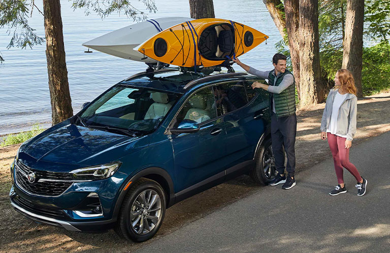 Couple enjoys 2021 buick Encore with surfboard up top