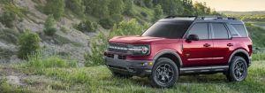 A red 2021 Ford Bronco driving in a forest area.