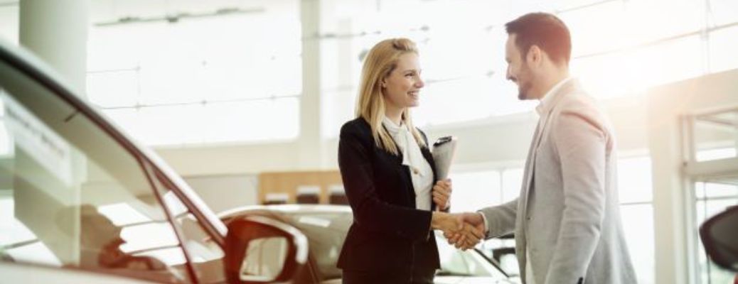 Dealership representative and customer handshaking after a successful deal signing