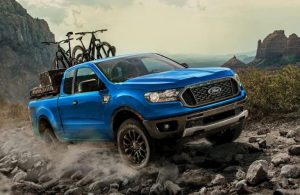 A blue 2023 Ford Ranger carrying cycles on rocky terrain.