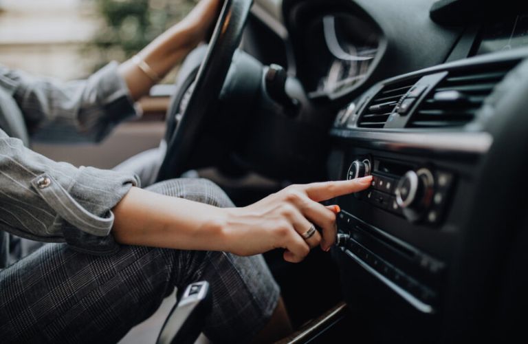 a driver's hand on a car's infotainment