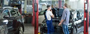 a man and technician talking at a dealerships service center