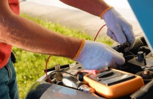 a technician wearing gloves jump starting a car