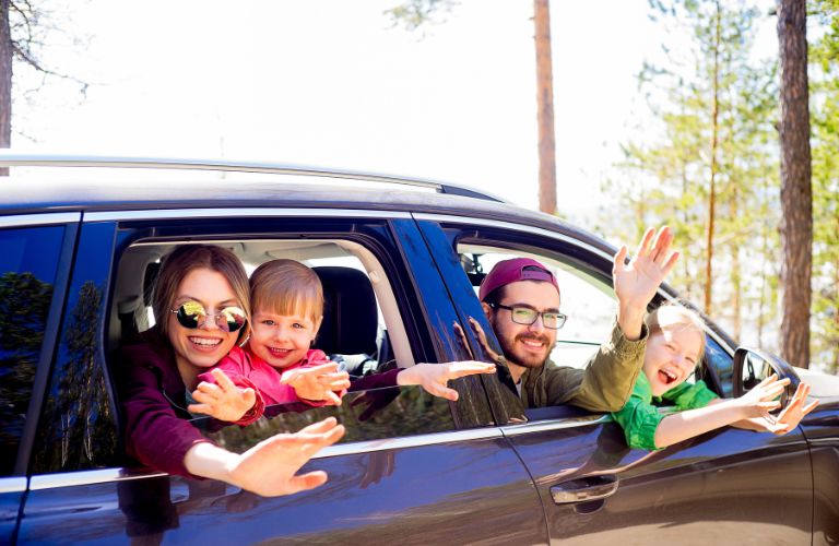 A happy family waving from a vehicle