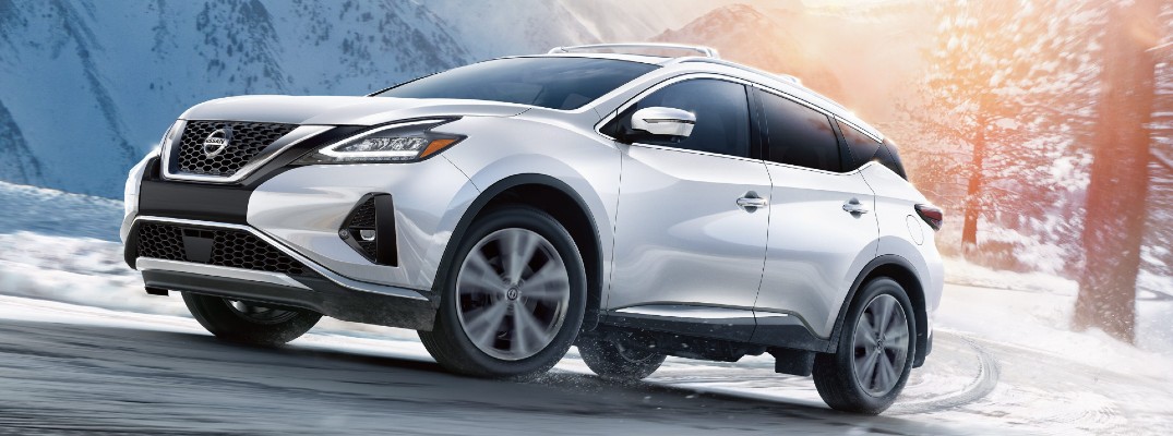 2020 Nissan Murano white paint driving on snowy road around curve with lens flare