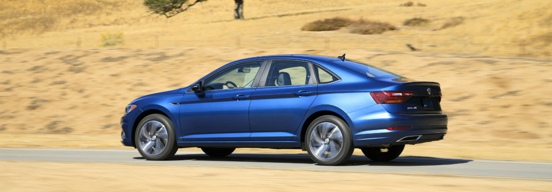 side view of a blue 2019 VW Jetta against a background of rock