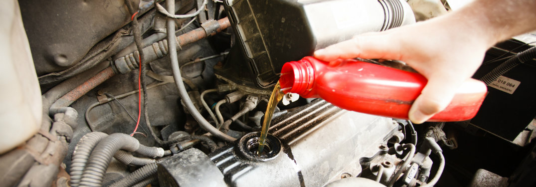 person pouring oil into engine