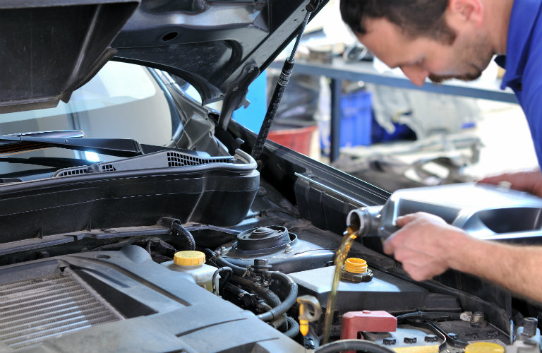 man putting oil into car engine