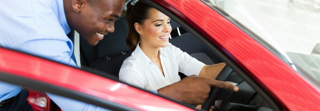Car salesman pointing out vehicle features to car shopper