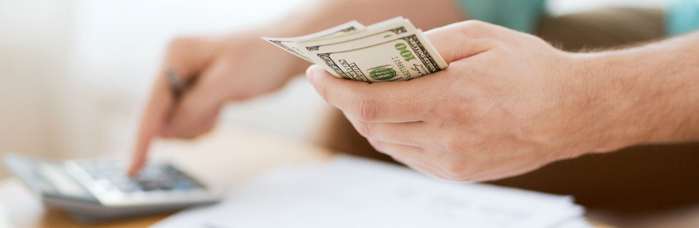 a man holding money and using a calculator
