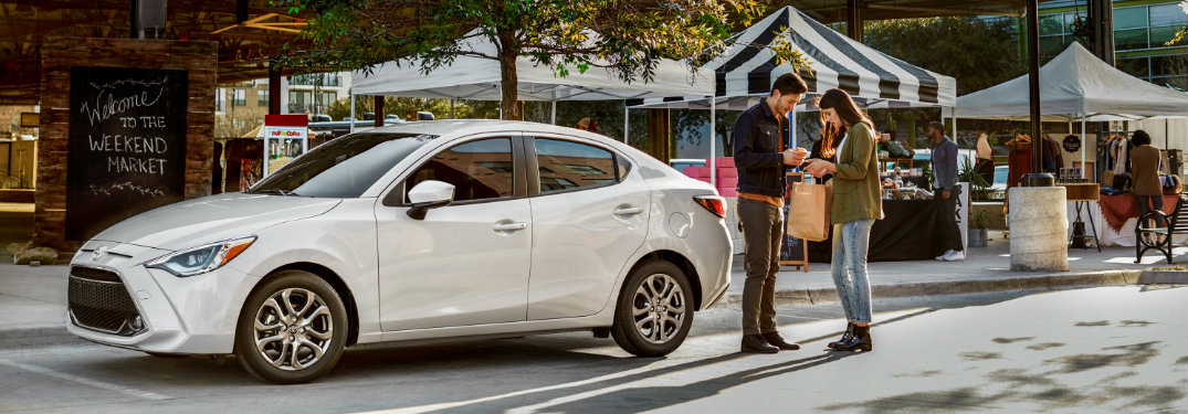2019 Toyota Yaris Sedan in white parked near a farmers market