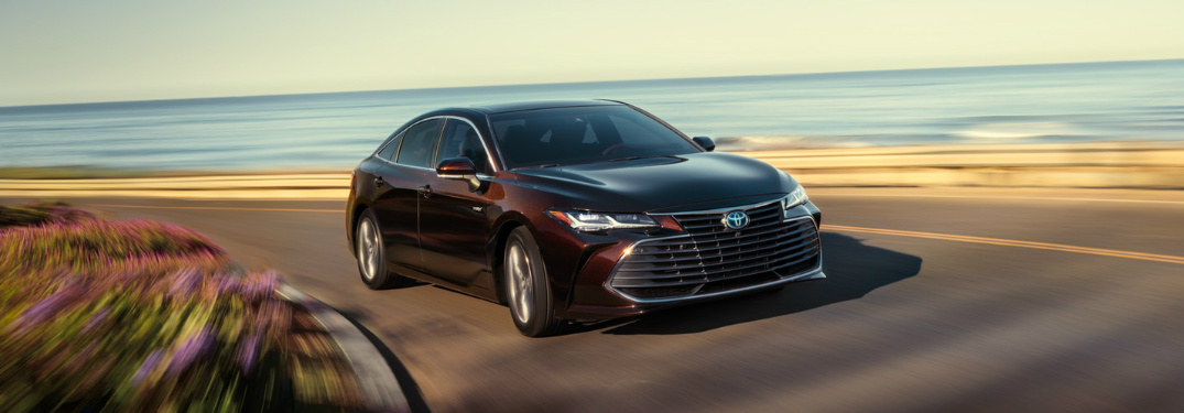 2019 Toyota Avalon in Opulent Amber driving on an oceanfront road
