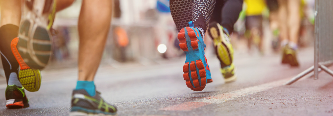 Close up show of a group of runners legs while they are running down the road