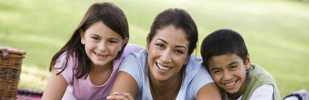 mother laying in the grass between two children