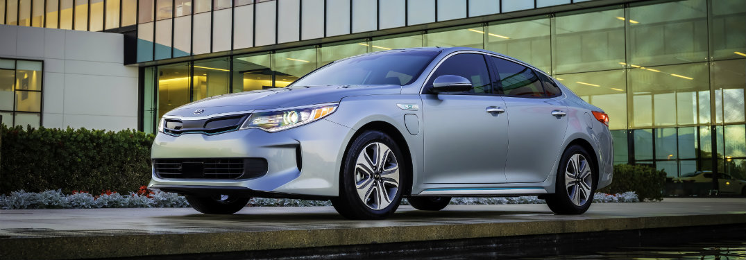 silver kia optima parked in front of glass building