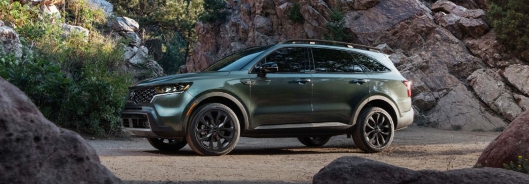 The side view of a dark green 2021 Kia Sorento parked near rocks.