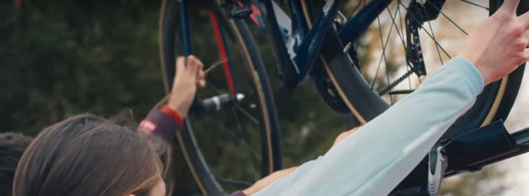 People Putting a Bicycle on the Roof Rack of a Mazda Vehicle