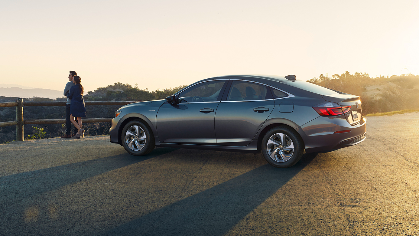 Image of a gray 2019 Honda Insight parked at a lookout point, with a young couple standing in front of it.