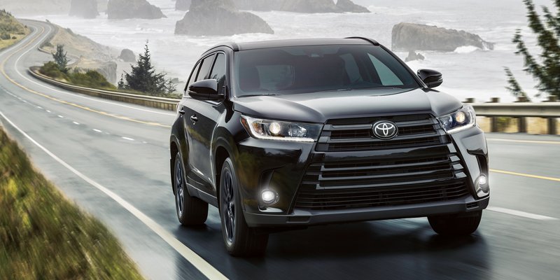 Image of a black 2019 toyota highlander driving along a misty coast.