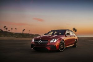 front view of a red-2018 Mercedes-Benz E-Class Wagon with the sun setting in the background