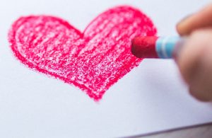 child drawing a red heart