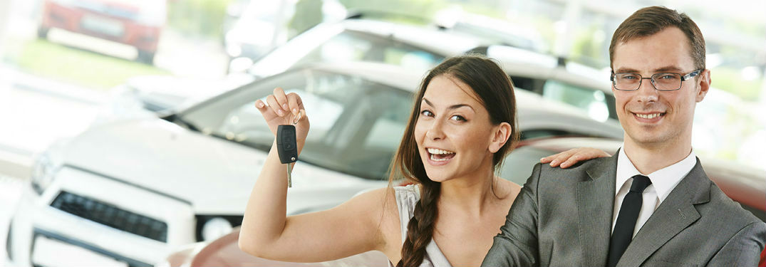 A man and woman standing in front of a car