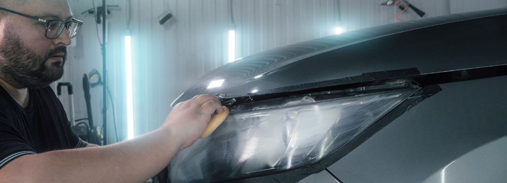 man cleaning the foggy headlights of his car